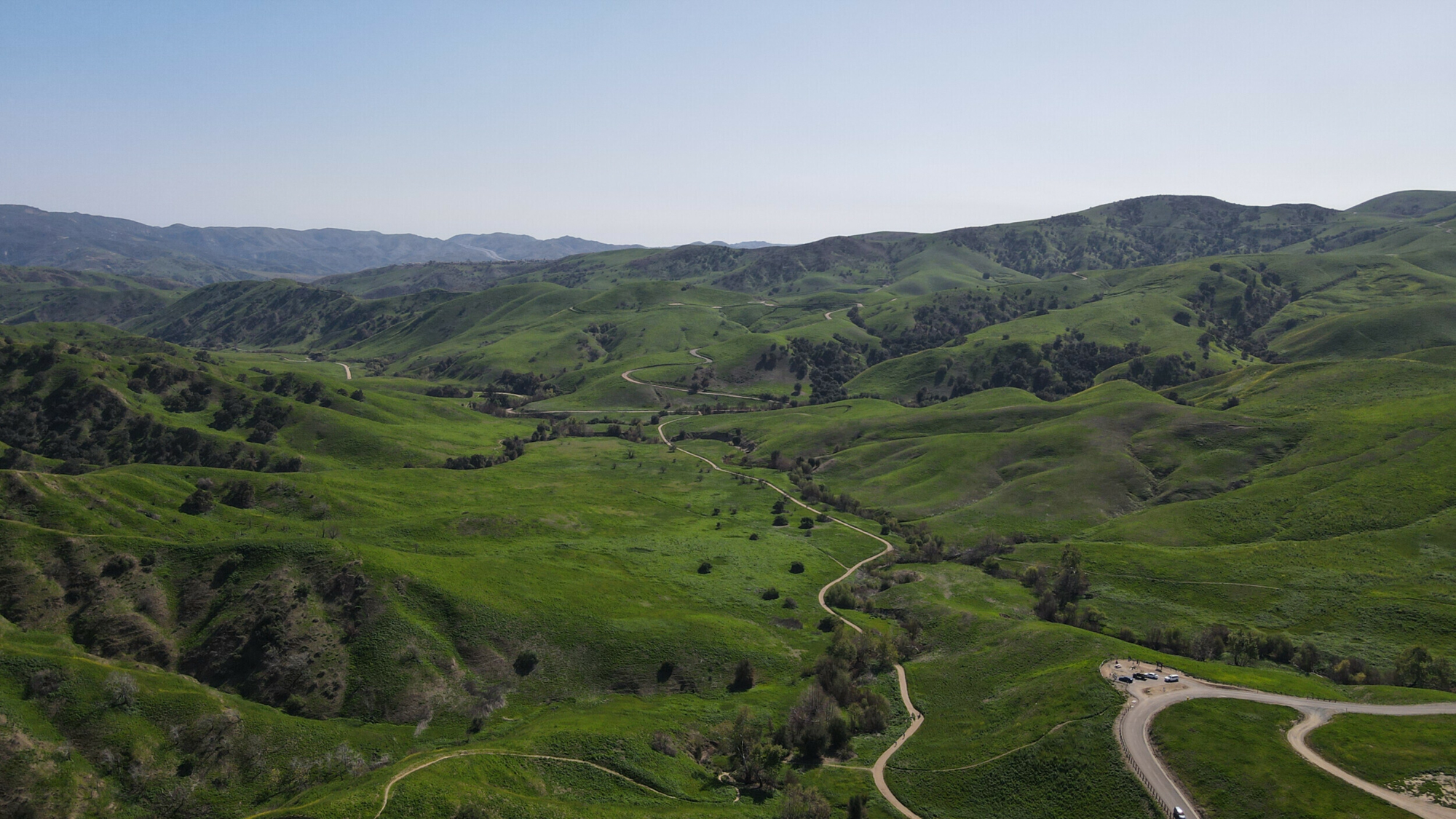 Aerial view of Chino Hills State Park showcasing lush green hills and a winding road taken by DJI Mavic Air 2 drone.