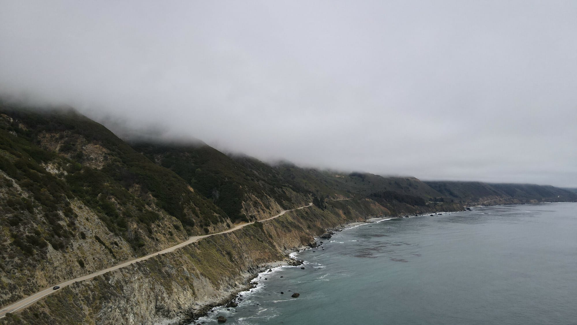 Aerial view of Highway 1 winding along the rugged coastline near Sand Dollar Beach, captured by DJI Mavic Air 2.