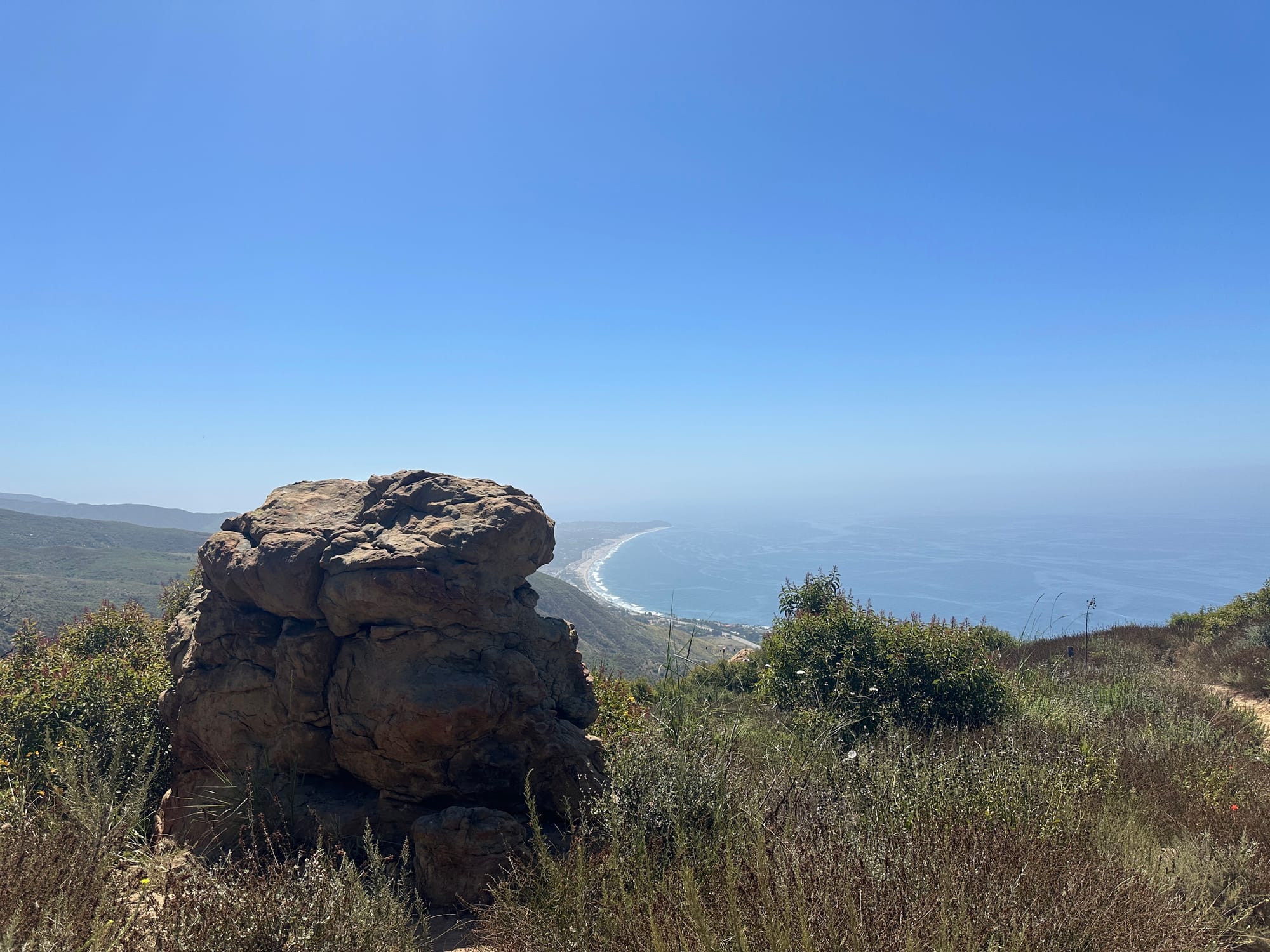 Trail signpost surrounded by wildflowers, with views of the Malibu coastline in the background at Charmlee Wilderness Park.