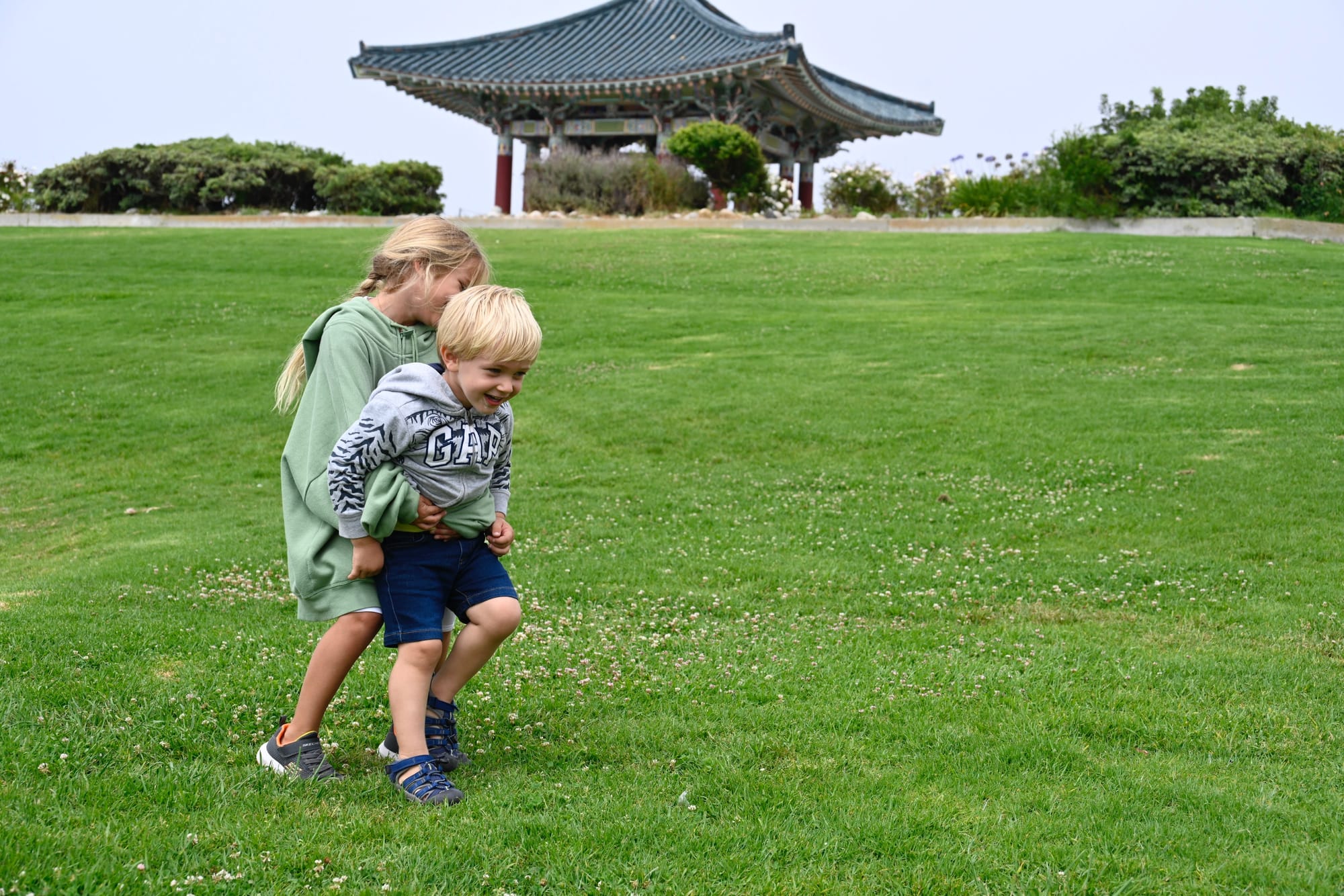 Children playing on the lawn with the Korean Bell of Friendship Pavilion, highlighting the family-friendly park atmosphere.