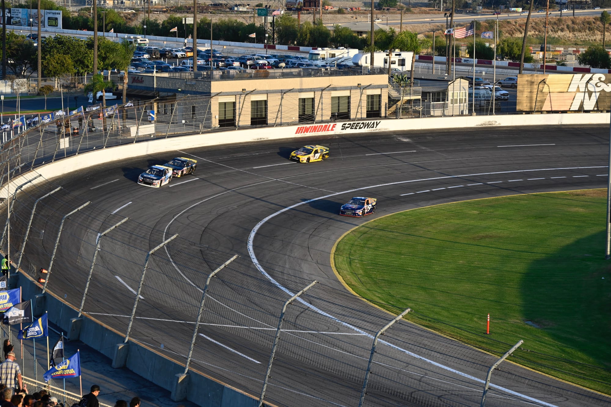 Race cars taking a turn on the track at Irwindale Speedway during the Night of Destruction event.