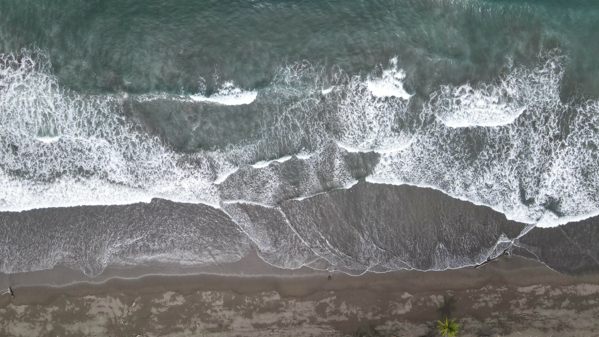 Aerial photo capturing the tranquil waves and deserted sands of Palo Seco Beach in Costa Rica, taken by DJI Mavic Air 2 drone