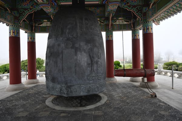 Close-up of the Korean Bell of Friendship in San Pedro, featuring detailed engravings and a traditional wooden striker.