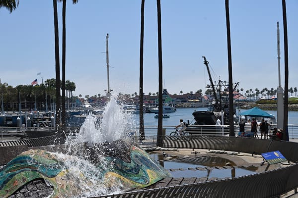 Scenic view of Long Beach harbor with a colorful fountain and boats, located near the Aquarium of the Pacific.