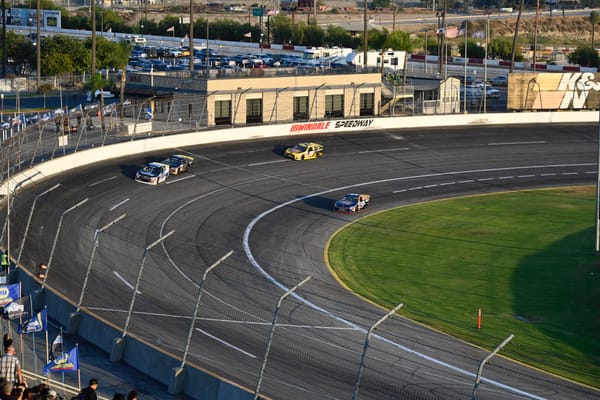 Race cars taking a turn on the track at Irwindale Speedway during the Night of Destruction event.