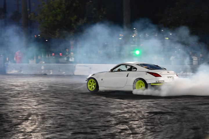 White car drifting with green rims at Drift Night in Irwindale Speedway, LA.